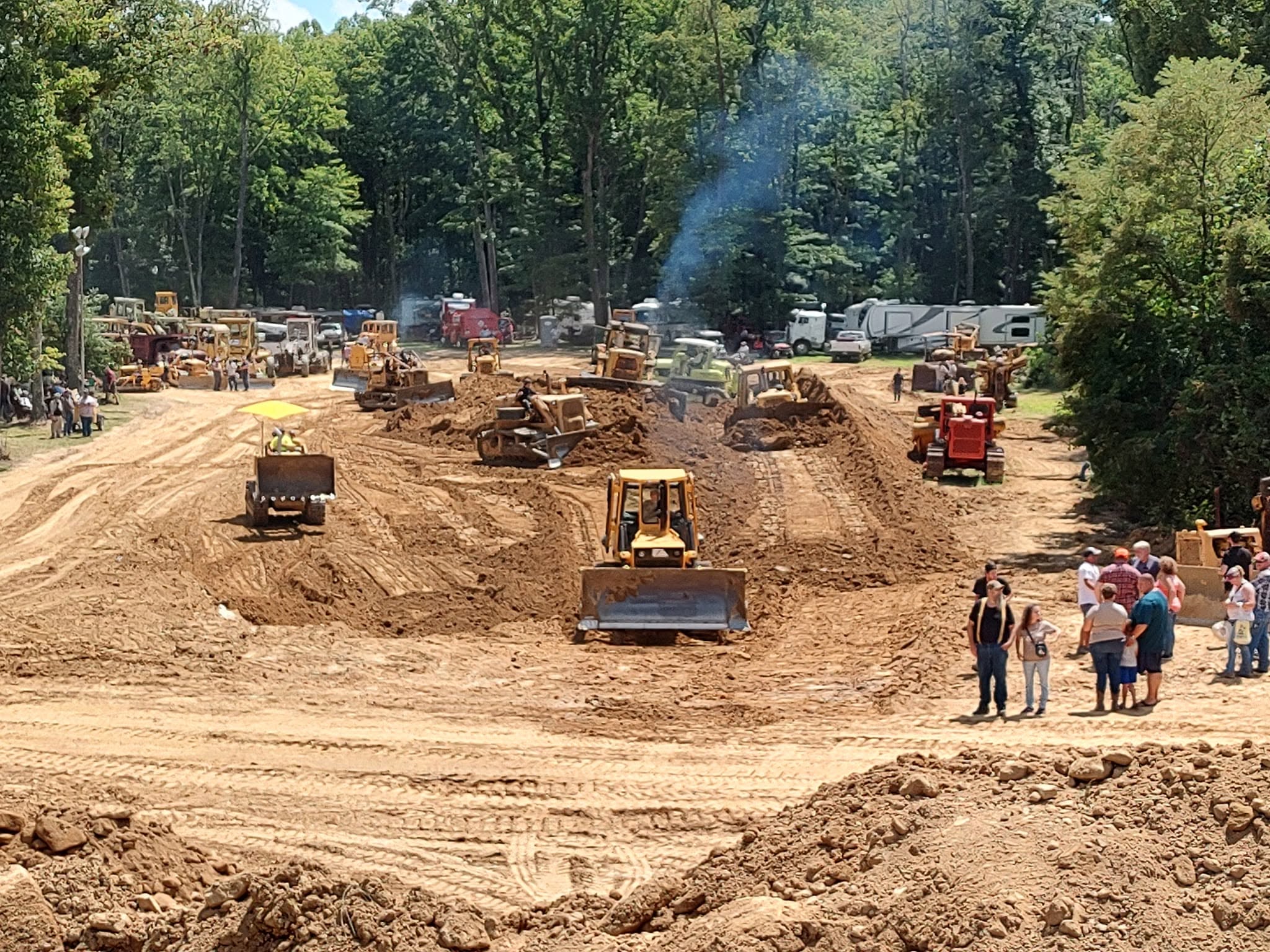 Multiple vintage bulldozers grading the demo field with spectators watching along the side