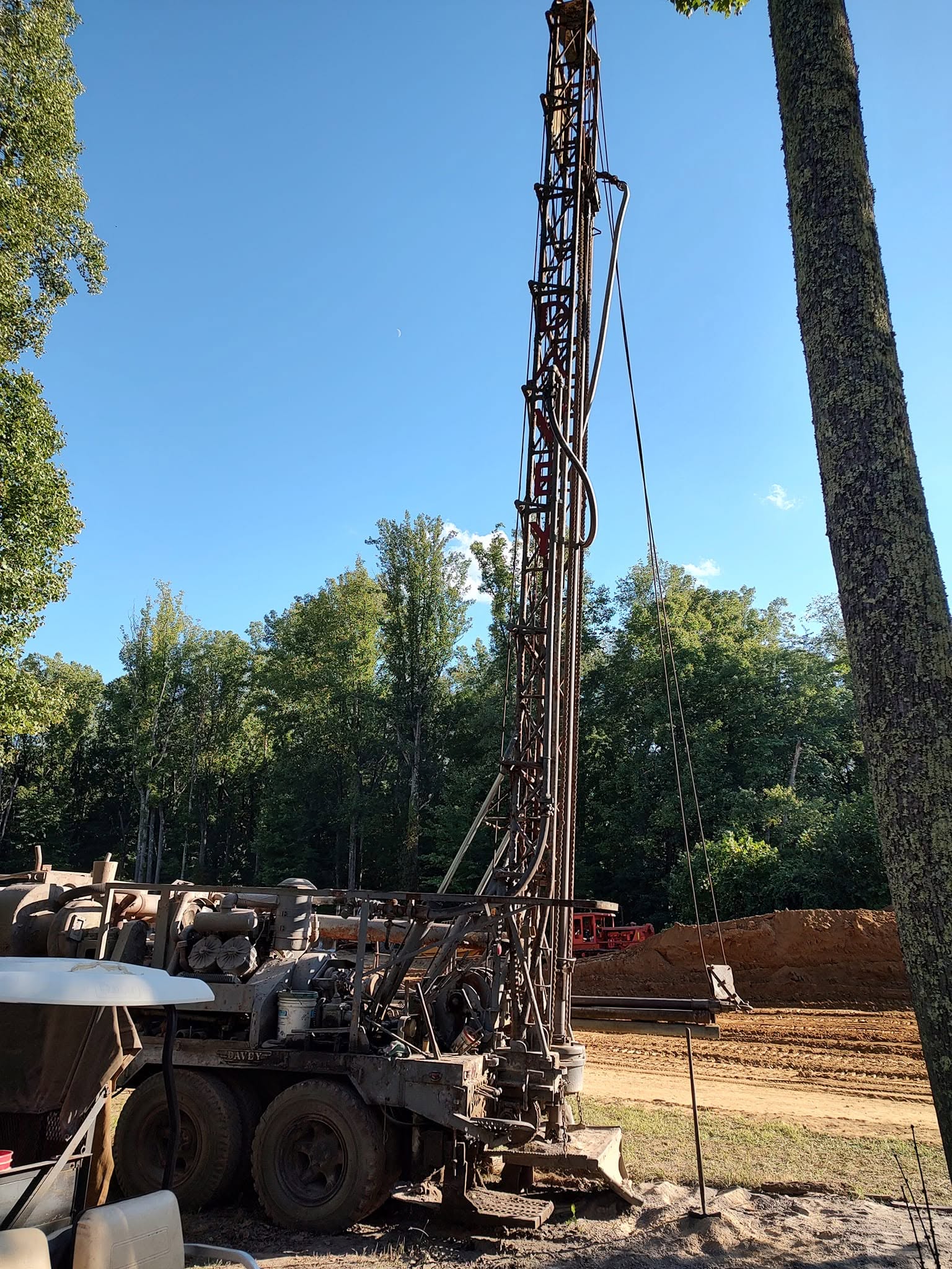 Tall antique well-drilling rig on tracks photographed against a clear blue sky