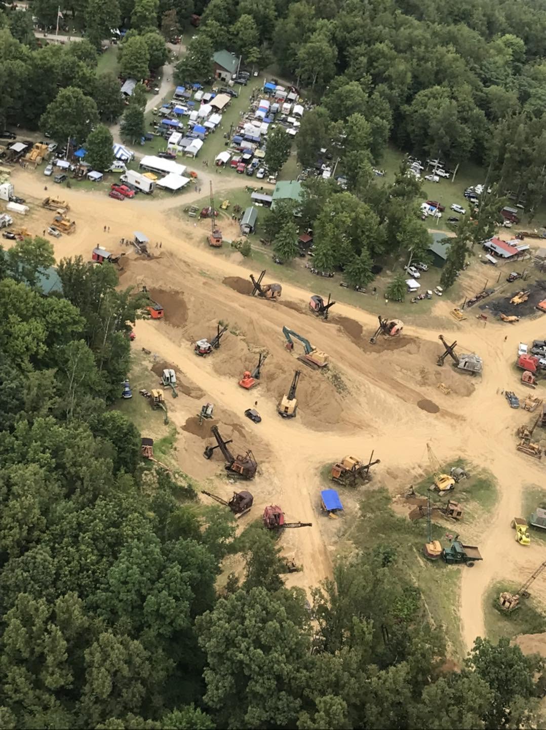 Aerial view angled toward the equipment demo field with cable cranes and dozers visible