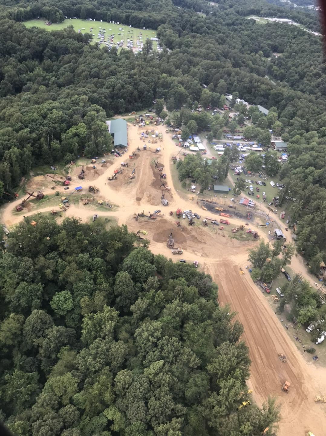 Wide aerial view showing the full demo field, vendor rows, and road alongside the property