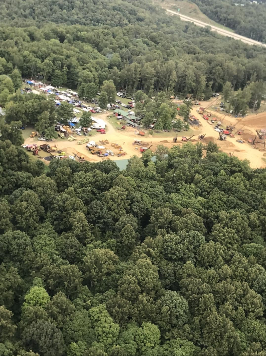 High aerial view looking down on the full show grounds surrounded by dense trees